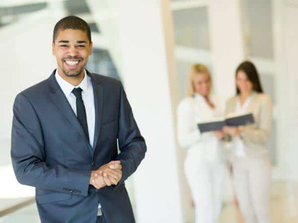 A happy smiling real estate investor and two realtors in the background.