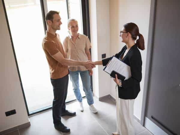 A happy couple is buying a home in Sofia and shake hands with a real estate agent.