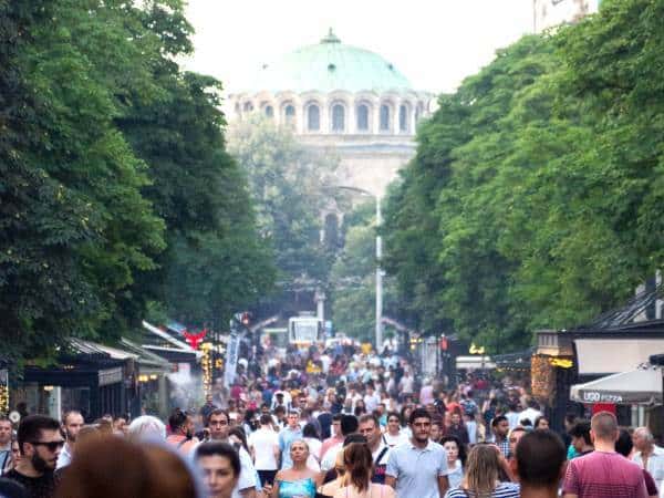 The boulevard Vitosha in Sofia by day, crowded, with a church in the background.