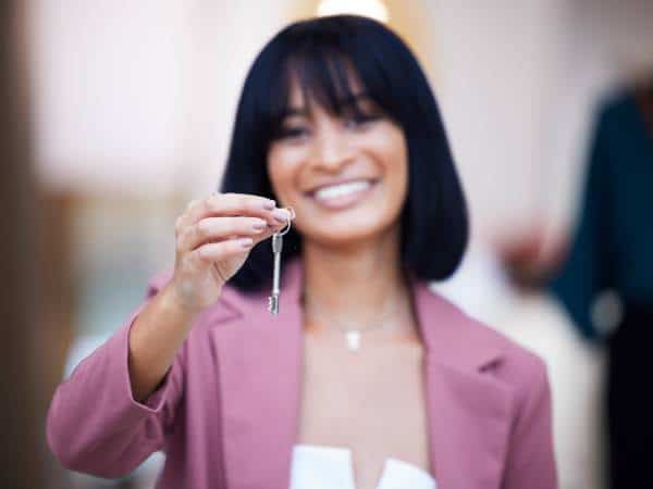 A smiling real estate investor holding a property key.
