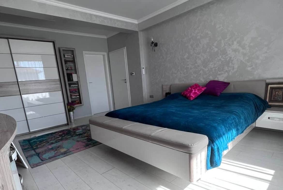 Grey bedroom with a closet and king sized bed