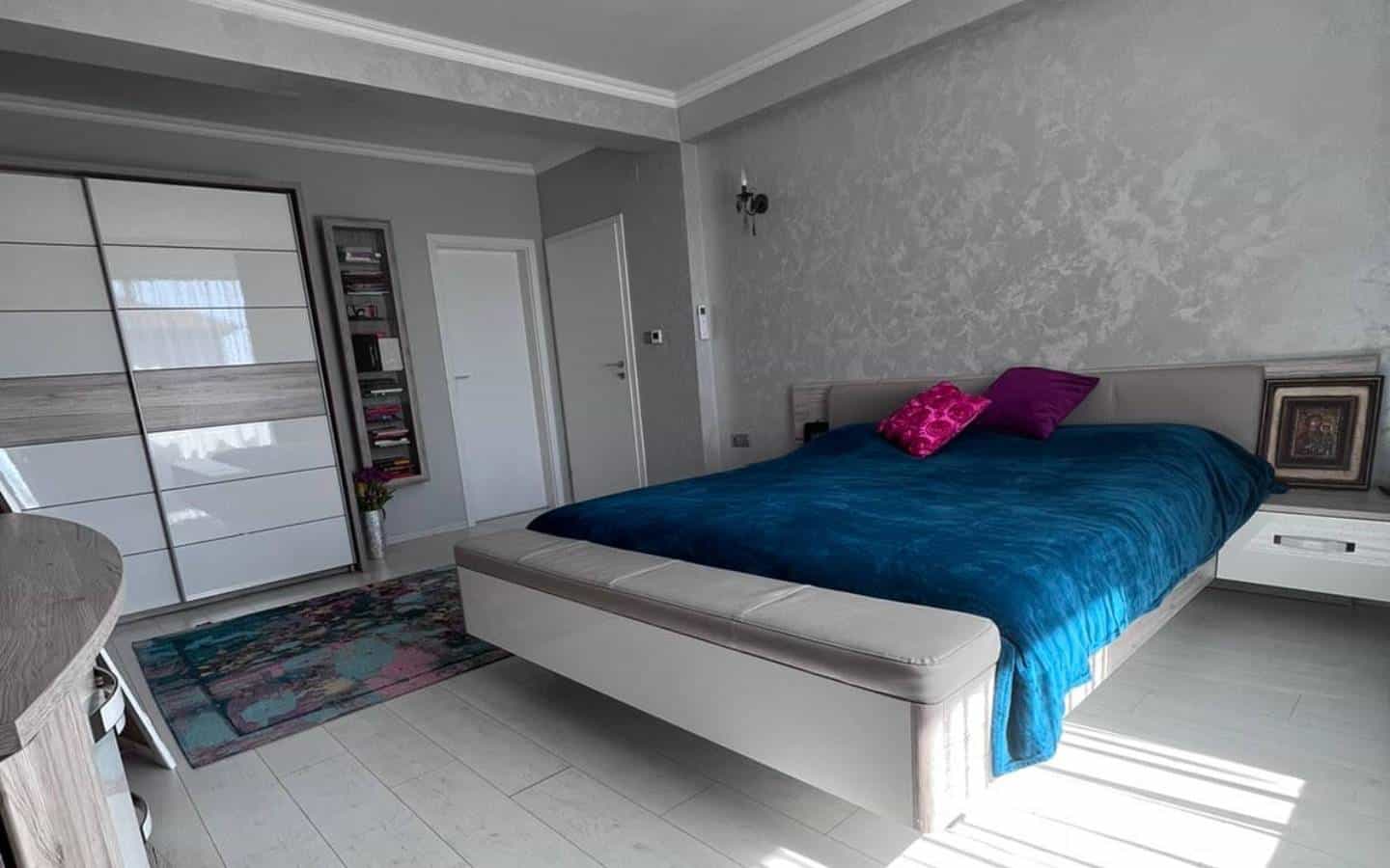 Grey bedroom with a closet and king sized bed