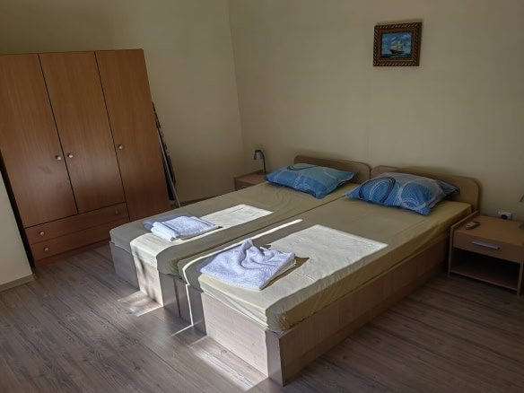 Спалня с две единични легла и голям кафяв гардероб.