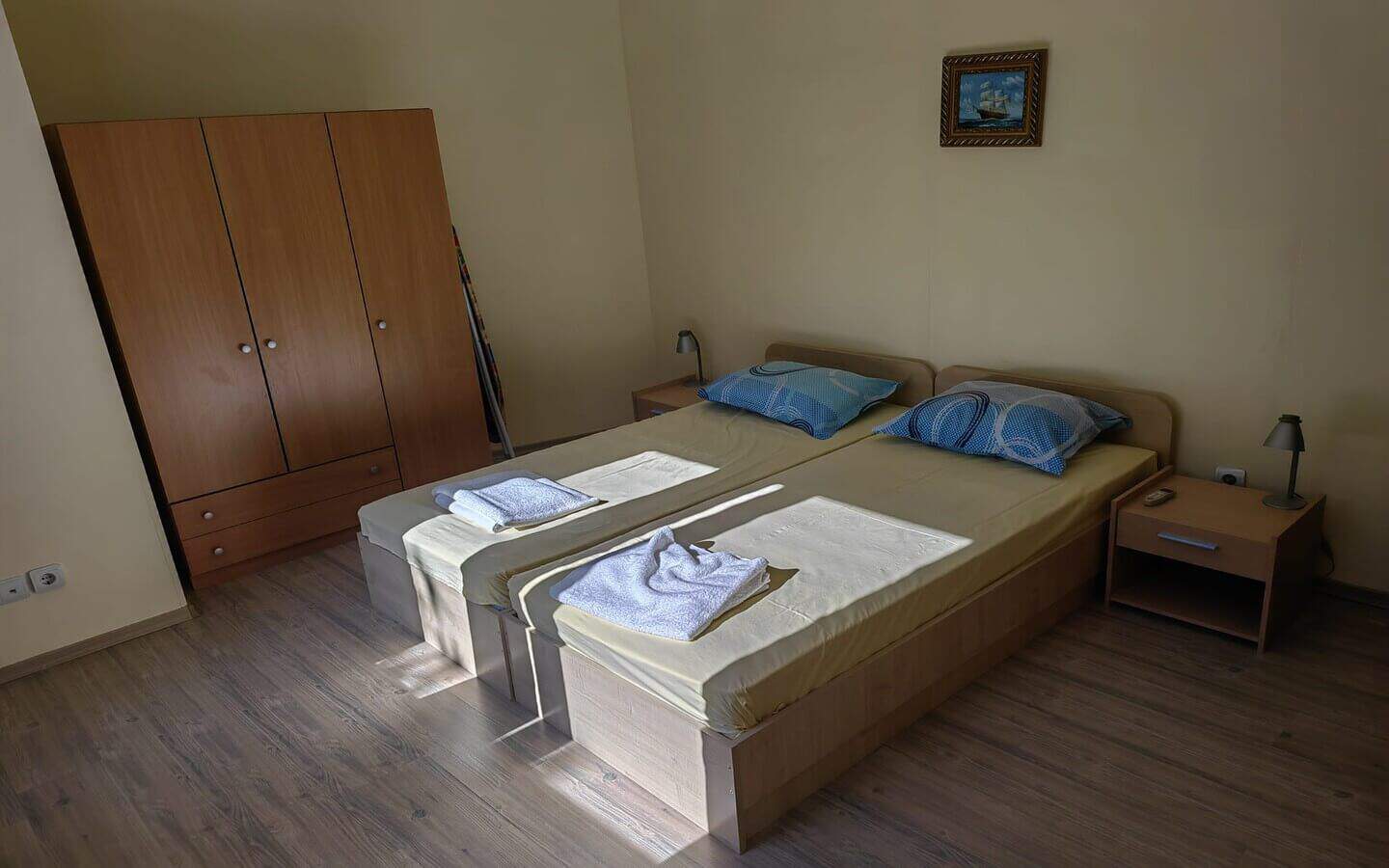 tristaen-apartament-prodajba-zlatni-pqsaci-2 Спалня с две единични легла и голям кафяв гардероб.