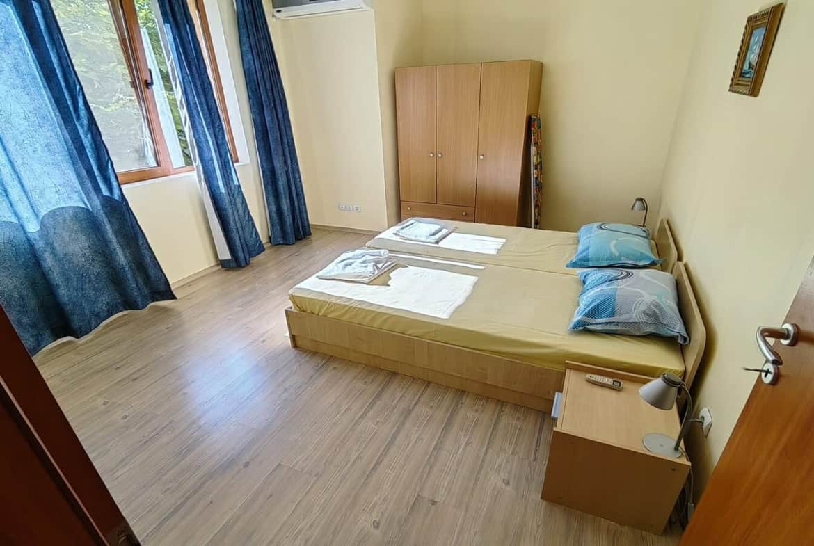 Спалня с две единични легла и голям кафяв гардероб.