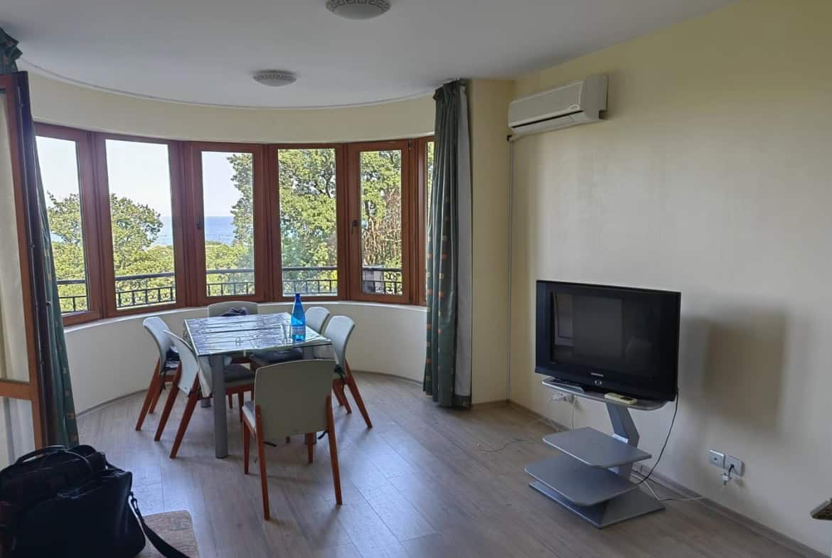 Обширна всекидневна с трапезарна маса и телевизор.