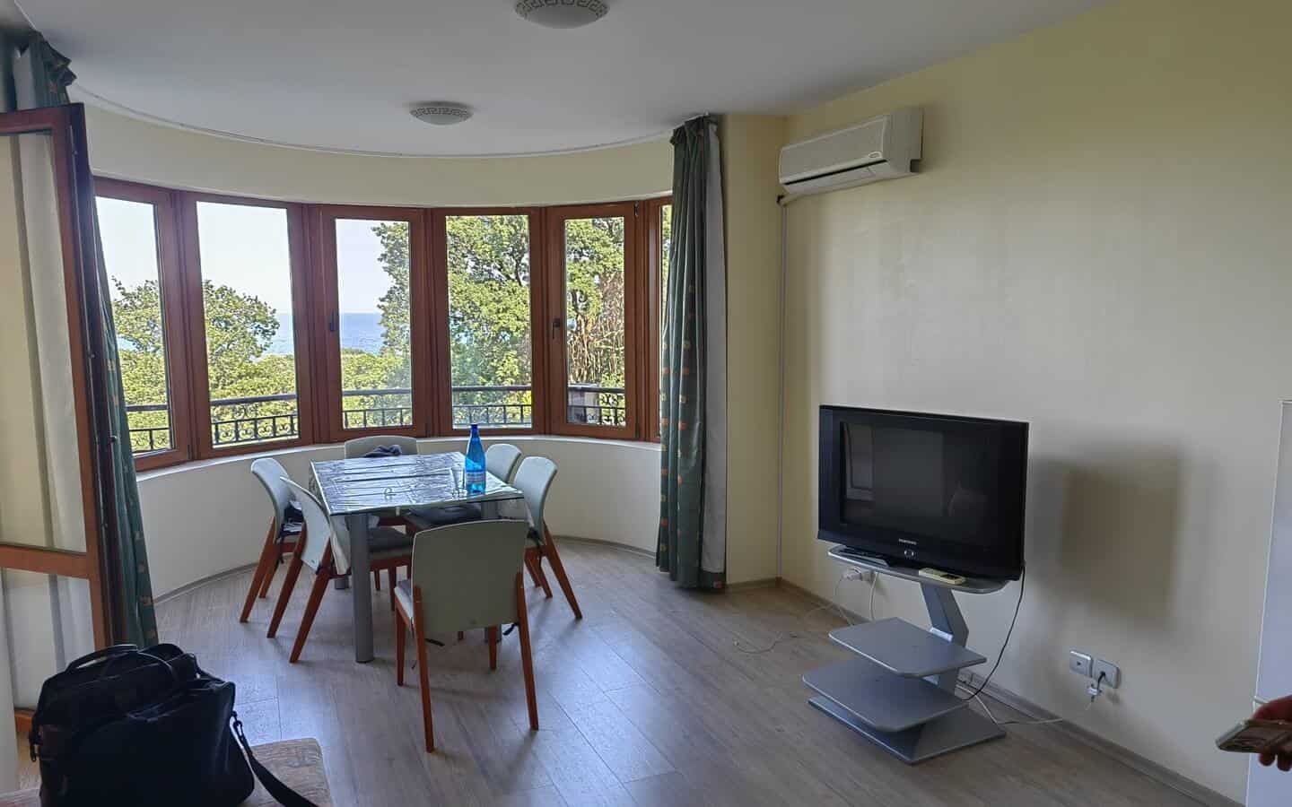 tristaen-apartament-prodajba-zlatni-pqsaci-5 Обширна всекидневна с трапезарна маса и телевизор.