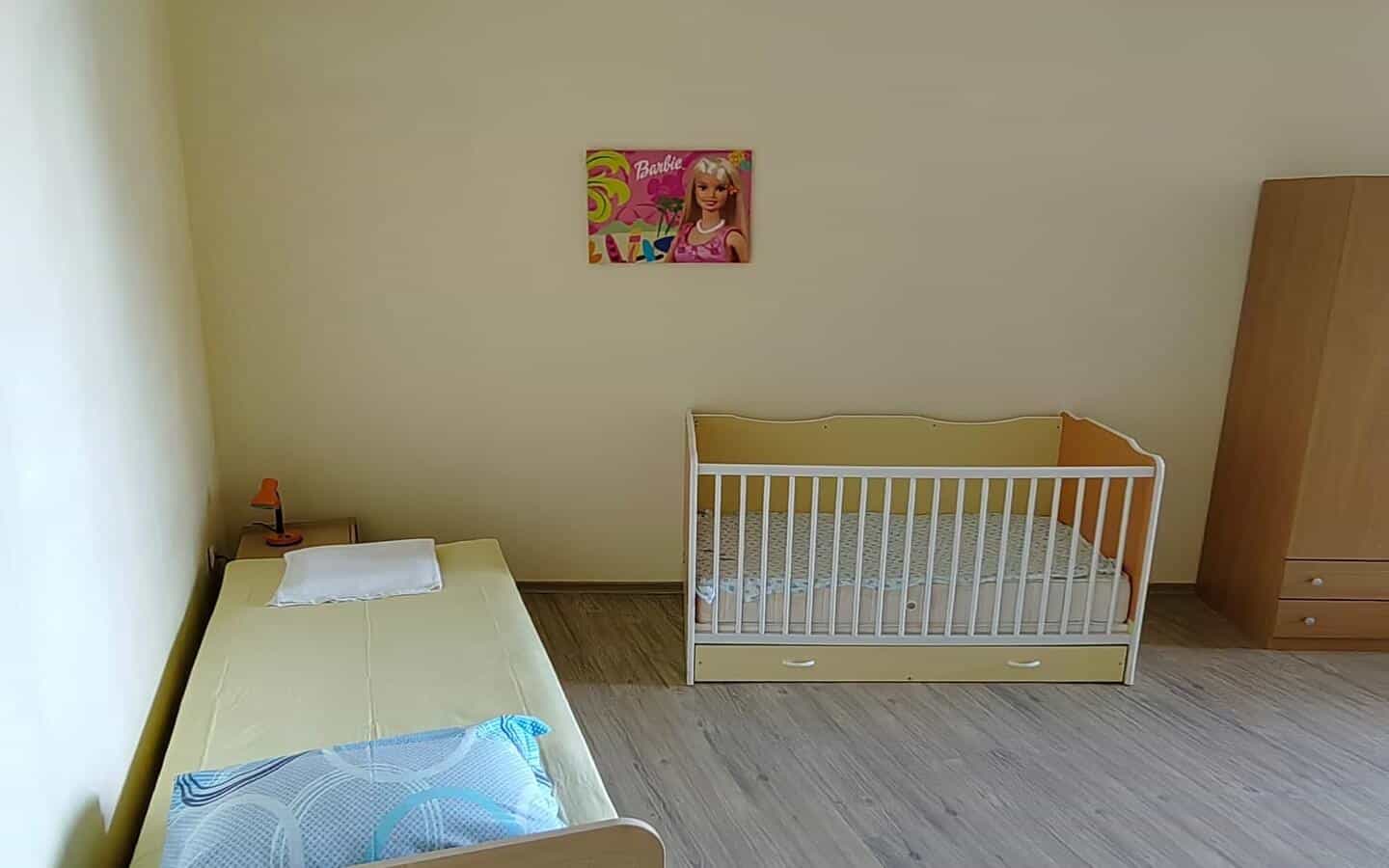 tristaen-apartament-prodajba-zlatni-pqsaci-8 Спалня с детско креватче и плакат на Барби на стената.
