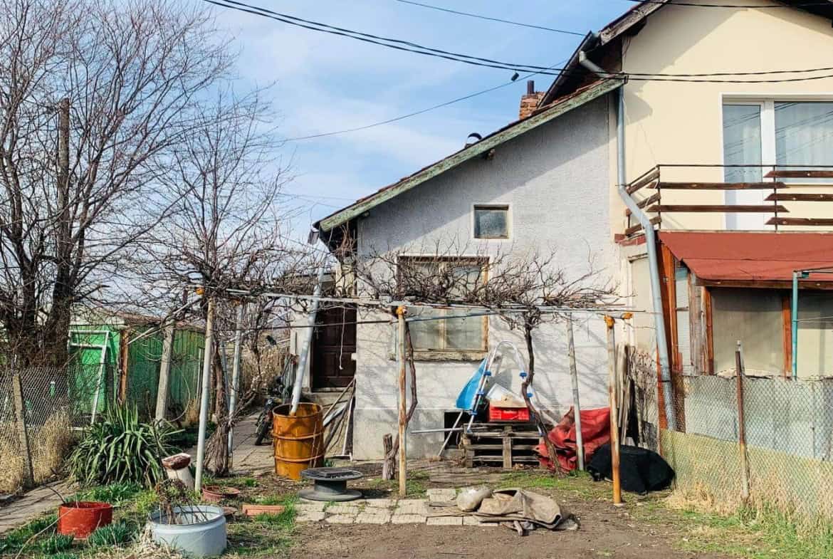 Къща с изглед към заден двор с ограда, множество дървета и външни съоръжения.