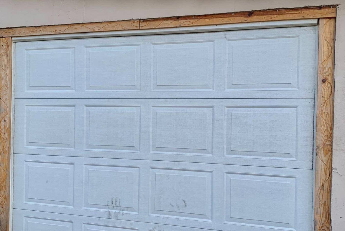 Затворена гаражна врата, около която има видими следи от употреба и износване.