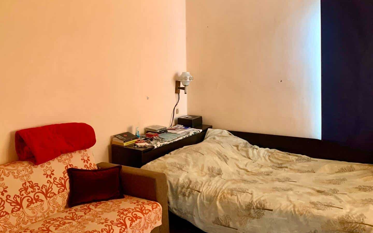 kushta-prodajba-kostinbrod-sofia-2 Спалня с розови стени, единично легло и малко червено диванче.