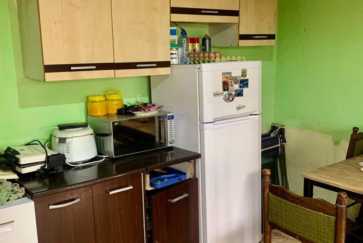 Друг ъгъл на кухнята с видим хладилник и малка трапезна маса.