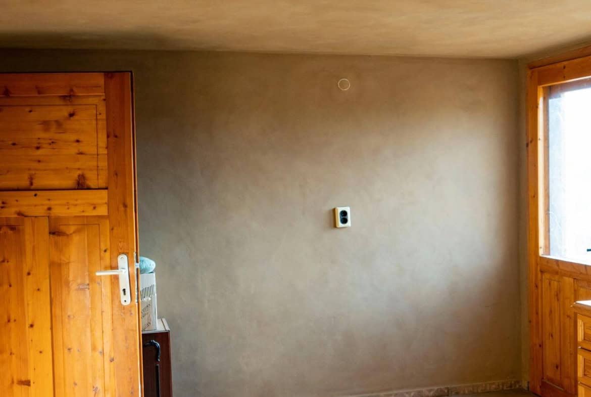 Просторна стая със светли стени и рустик мебели.