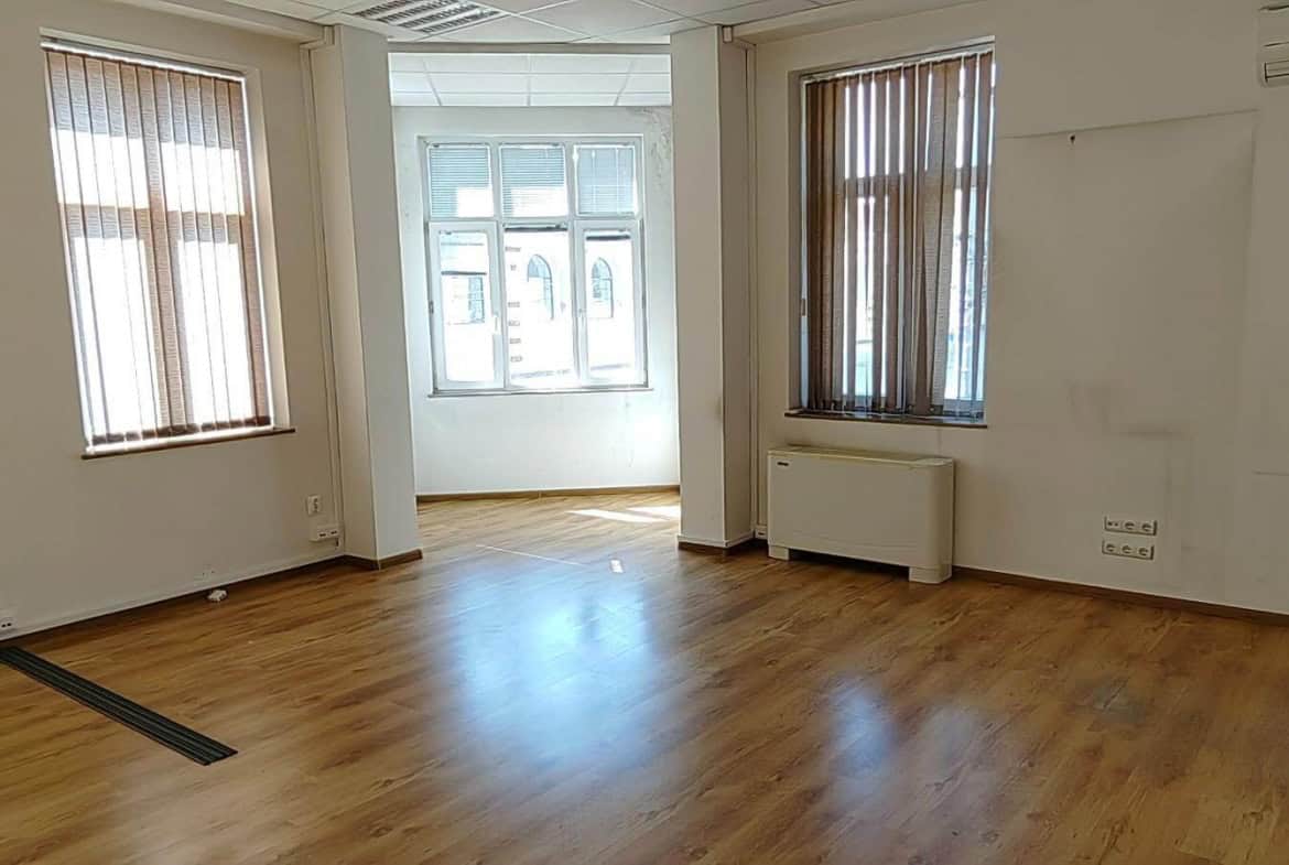 Empty room with wooden floor and three windows from office for rent in Sofia near Central Halls.