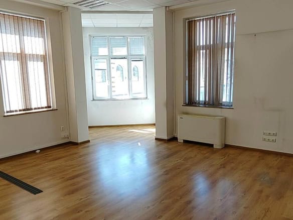 Empty room with wooden floor and three windows from office for rent in Sofia near Central Halls.