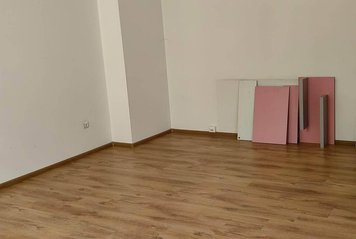 Празна стая с дървен под и няколко цветни плоскости до стената от офис под наем в София до Централни хали.