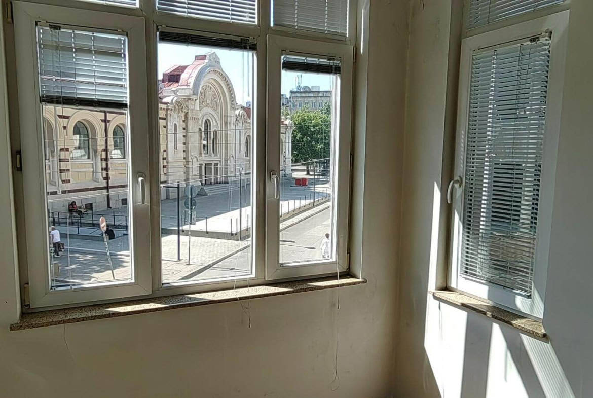 Ъгъл на празна стая с прозорци, гледащи към улицата от офис под наем в София до Централни хали.