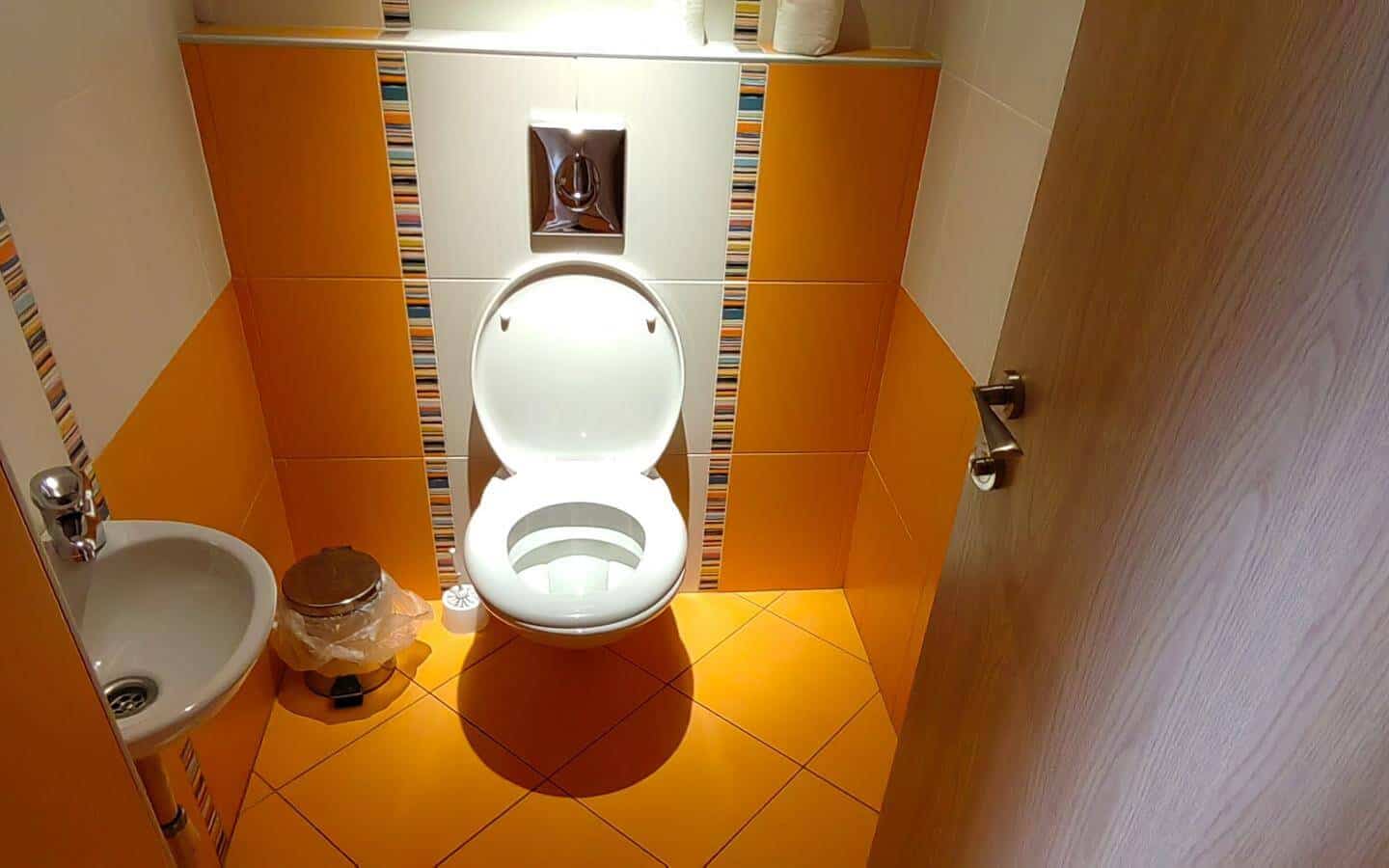 алка баня с оранжеви плочки и тоалетна от офис под наем в София до Централни хали.