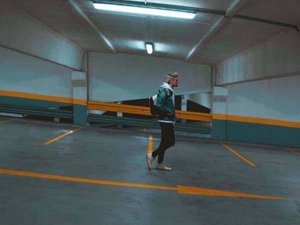 A man walk in an underground parking garage.