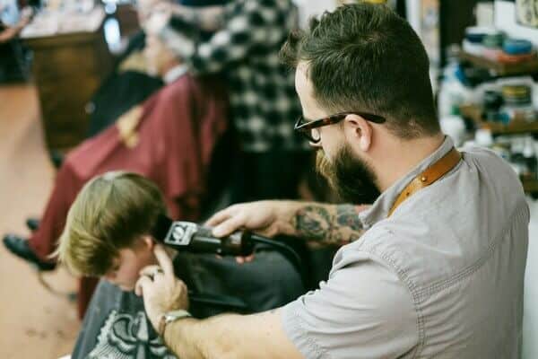 A hairdresser cut the hair of a little boy in a shop in Sofia.