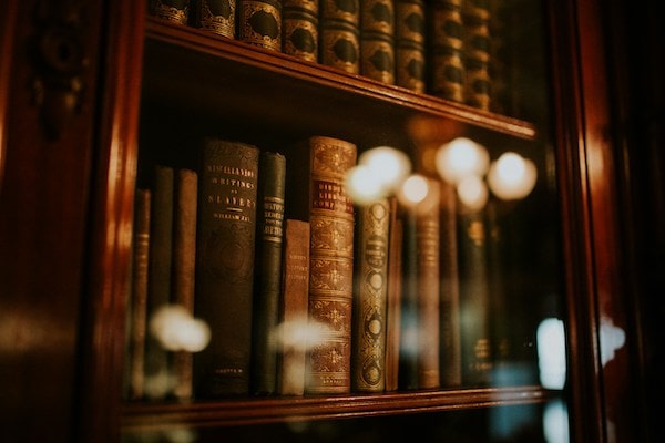 Old academic books on a wooden shelf.