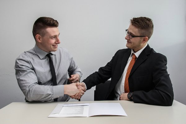 A real estate agent and his client shaking hands.