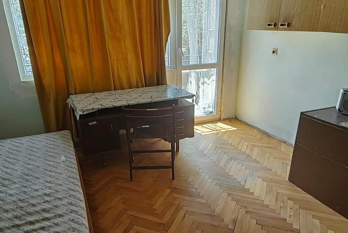 Стая с легло, бюро, стол и прозорец с пердета.