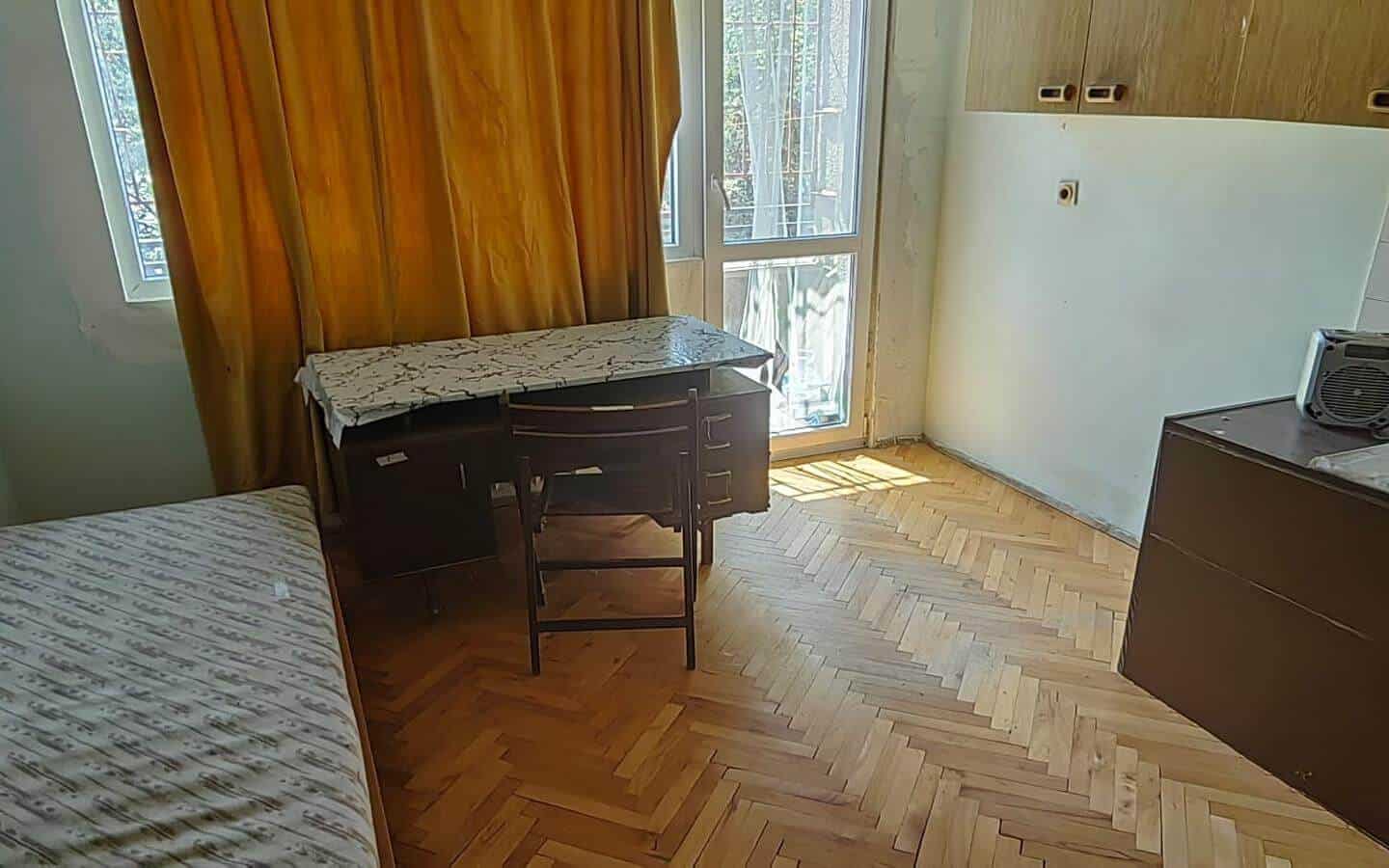 Стая с легло, бюро, стол и прозорец с пердета.