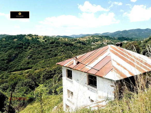 White house with rusty roof in mountainous countryside landscape