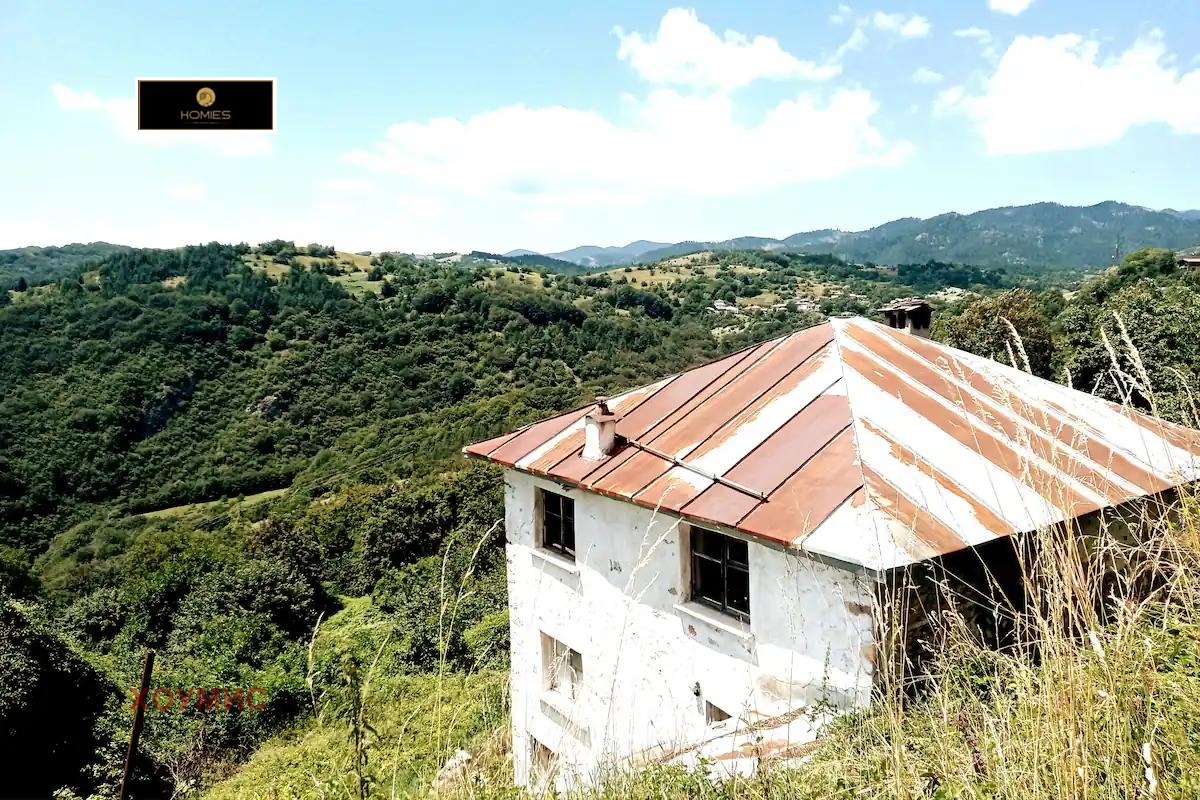 White house with rusty roof in mountainous countryside landscape