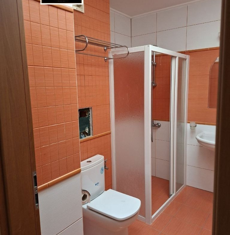 Orange tiled bathroom with shower cabin and toilet
