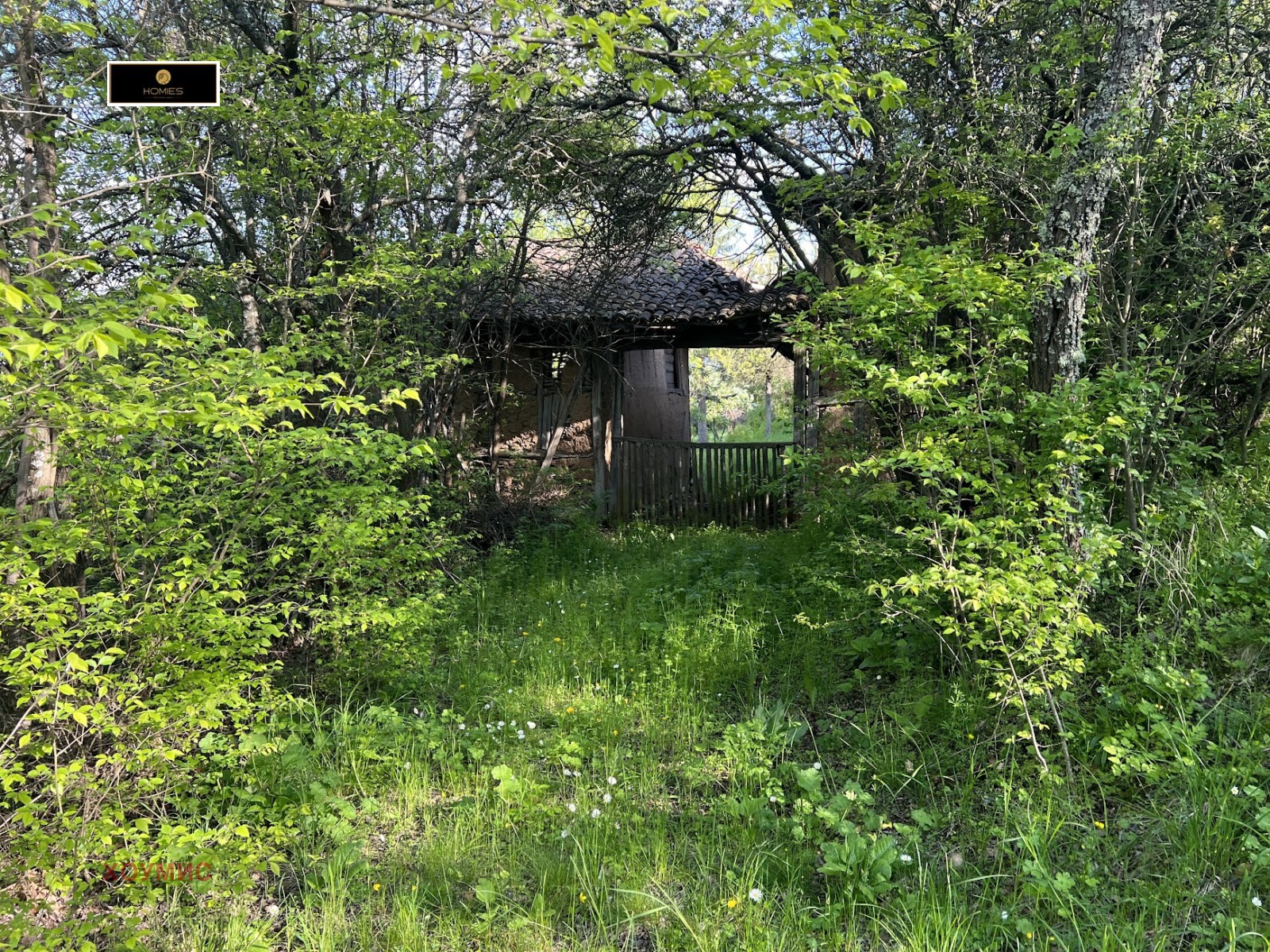 Полусрушена сграда с бели стени и дървена верандка