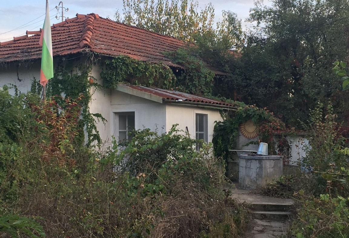 Overgrown house with red tile roof needs renovation