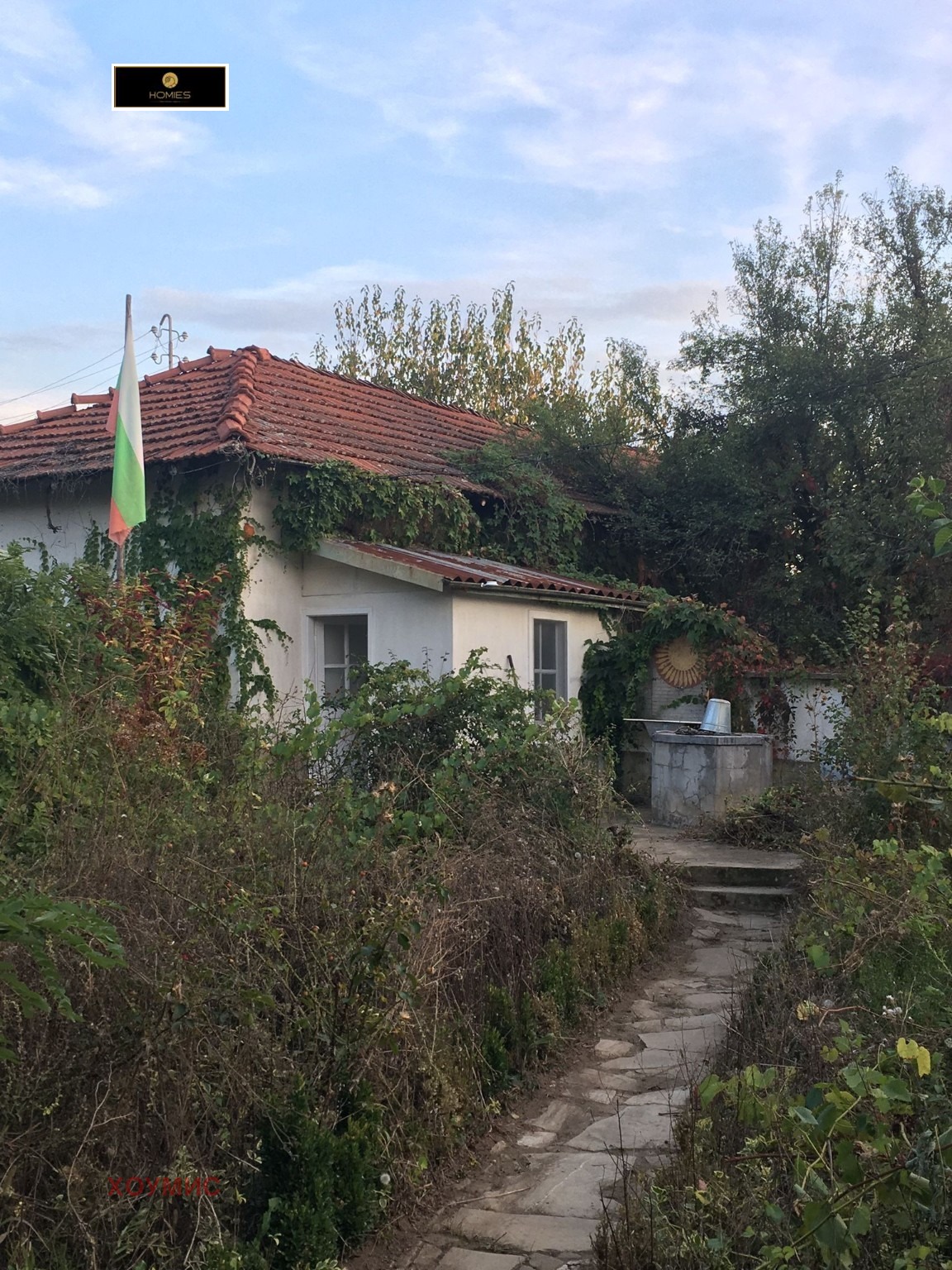 Overgrown house with red tile roof needs renovation